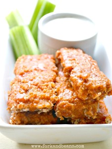 A plate of baked buffalo tempeh tenders with celery sticks and blue cheese dressing.
