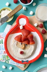 Brighten up your kids' Christmas morning with these Santa Bagels. Smothered with cream cheese and fresh fruit, this is one breakfast that is guaranteed to be on the Nice list this year #christmasbreakfast #funfood #kidfood