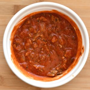 A bowl with marinara sauce and the ground turkey meat