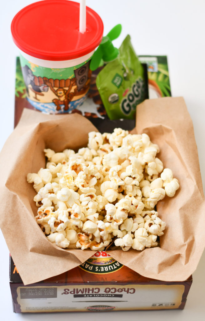 An empty cereal box made to be a popcorn and drink holder for movie night.