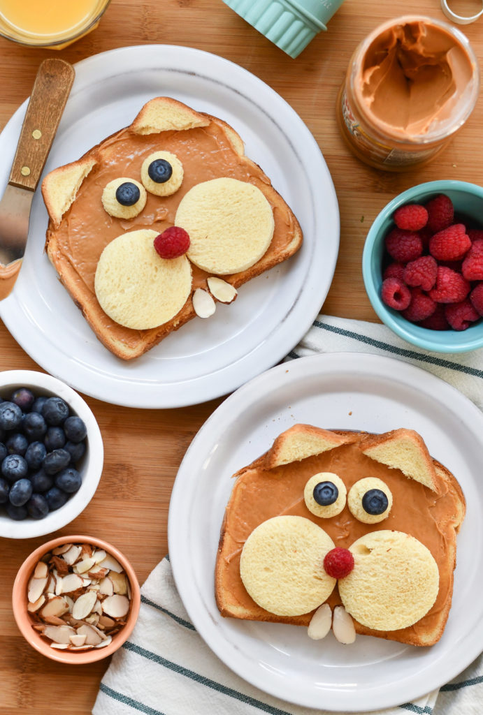 Two plates with toast made to look like groundhogs on a table with fruit in a bowl.