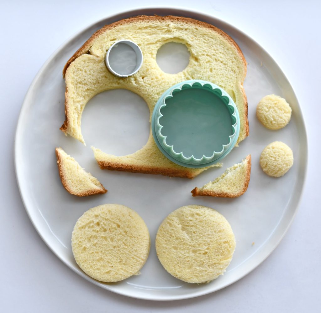 A plate with a piece of bread that is cut into circles on a white background.