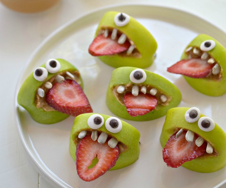 A plate of cut apples made to look like silly faces with strawberry tongues