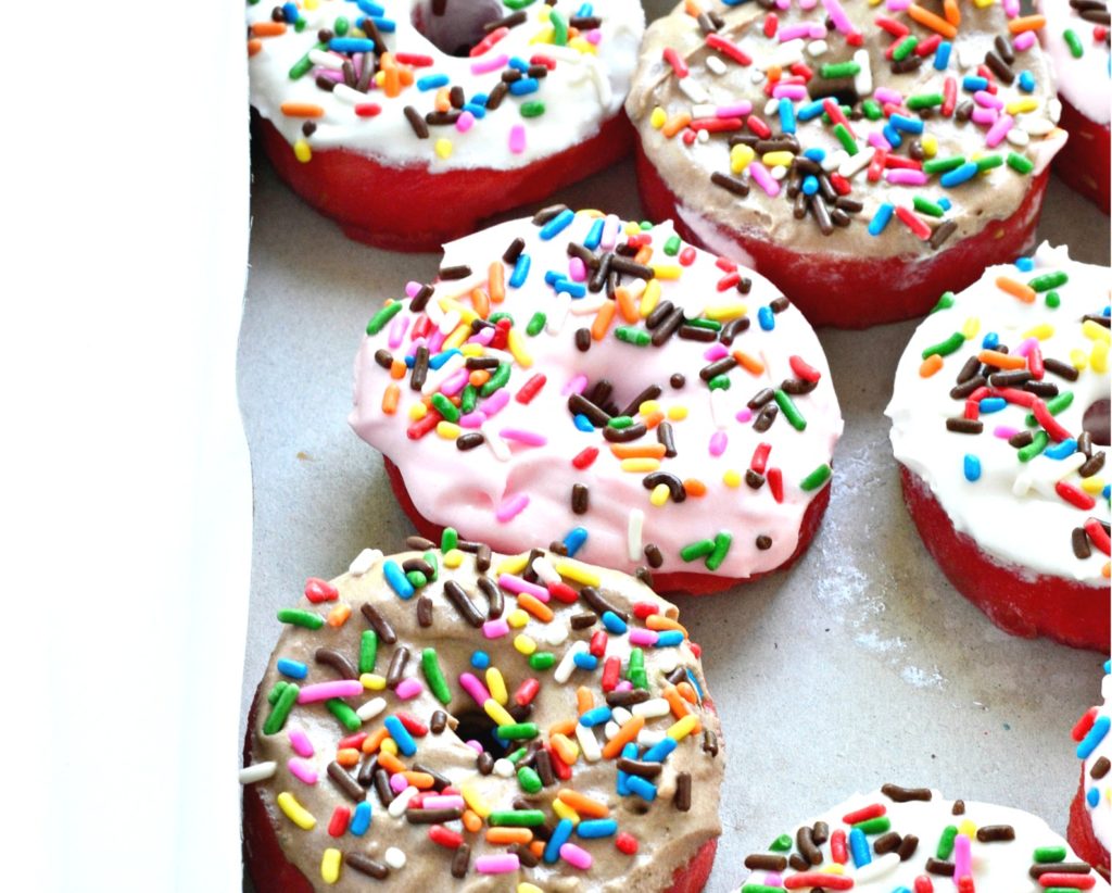 A box of watermelon cut into donut shapes, topped with whipped cream and sprinkles