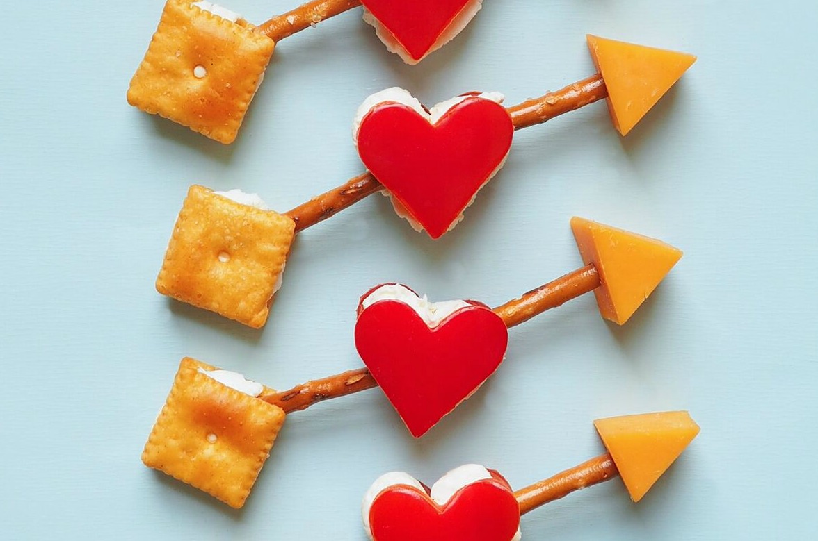 Bell pepper hearts held by pretzel sticks and cheese cracker arrows.