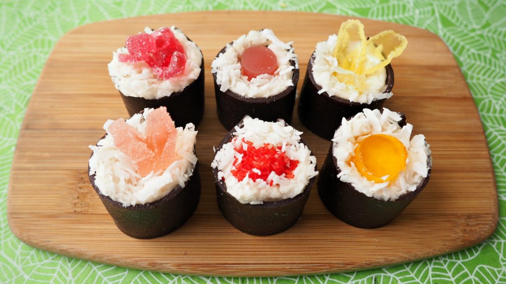 A cutting board with Cake Sushi on top made with cake, fruit leather, and gummy candies