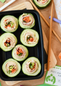 A black container with 7 Cucumber Sushi rolls on top of a lunchbox theme.