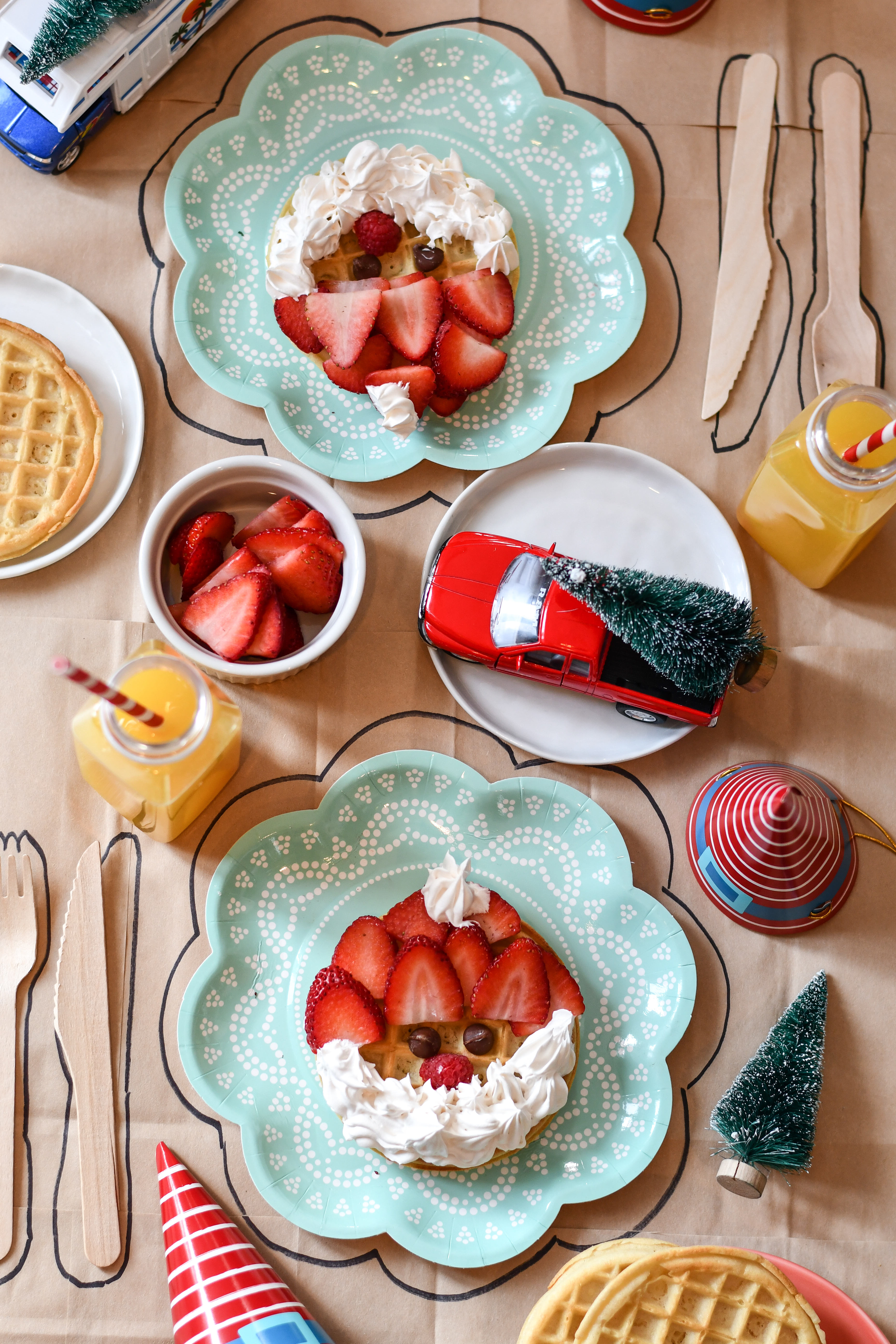 A table set with 2 plates and Christmas Breakfast Waffles made from frozen waffles, strawberries, and a whipped cream beard.